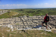 Walker on Malham Cove, limestone cliffs, Malhamdale